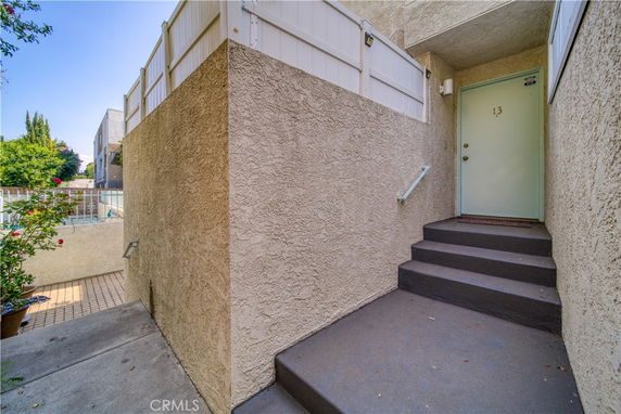 Entrance to a building with a tan stucco exterior and steps leading to a door labeled 13.