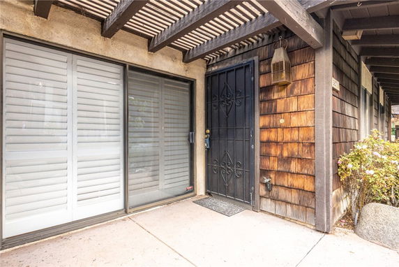 Front view of a house entrance with a black security door and wooden siding.