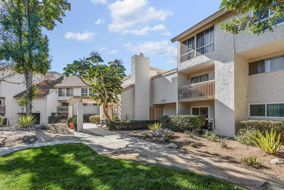 Front view of a multi-story residential building with balconies and landscaping.