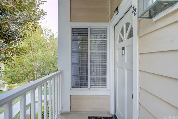 Front view of a house entrance with a white door and window, surrounded by light-colored siding.