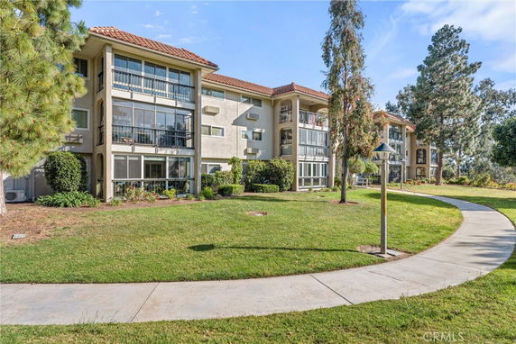 Front view of an apartment building with multiple balconies and large windows.