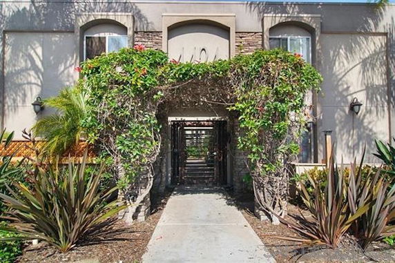 Front view of a building entrance with arch covered in greenery.