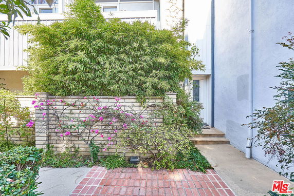 Front view of a building with a small brick path and greenery.