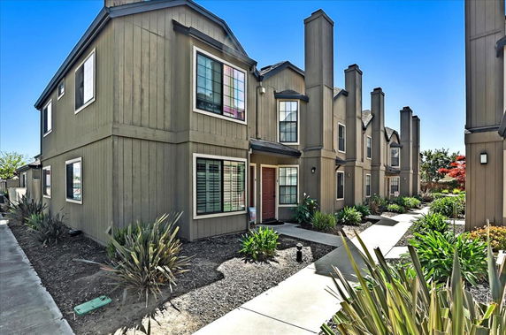 Front view of multi-story townhouses with chimneys and windows.