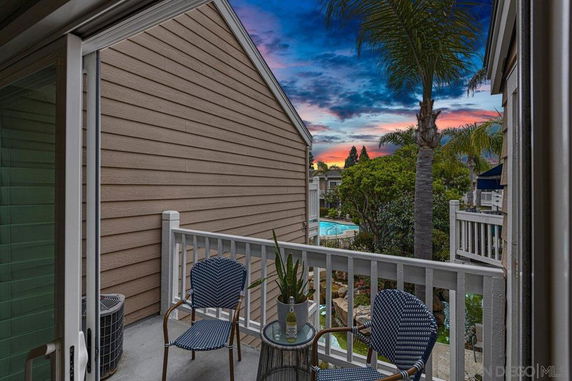 Outdoor balcony with chairs overlooking a pool and garden area.