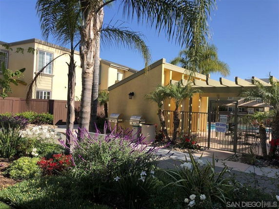 Outdoor view of a residential area with a gated swimming pool and landscaped garden.