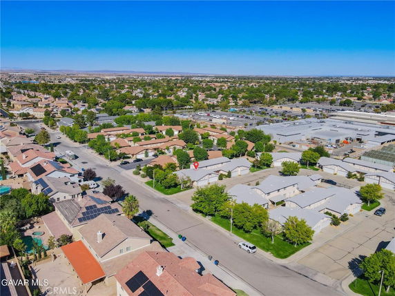 Aerial panoramic view of a residential neighborhood with houses, streets, and nearby commercial buildings.