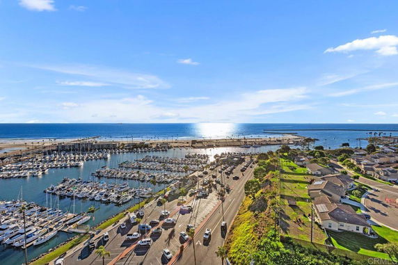 Panoramic view of a coastline with a marina, ocean, and residential area.