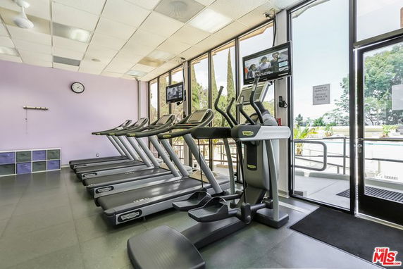 Indoor gym area with treadmills and large windows.