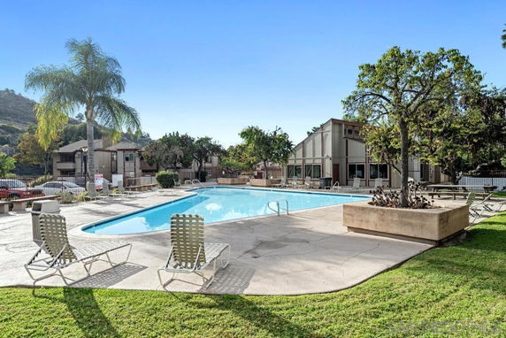 Outdoor swimming pool area with surrounding chairs and greenery.