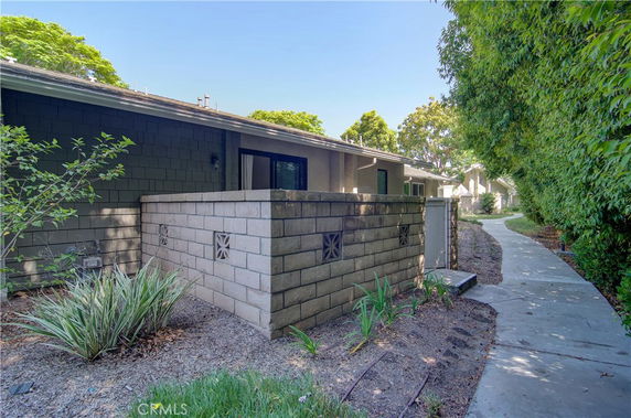 Front view of a single-story house with a brick fence and pathway.