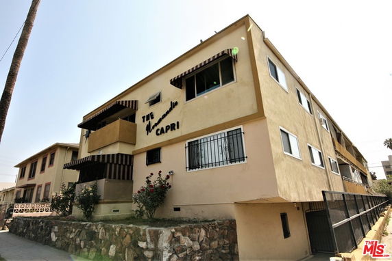 Front view of a multi-story apartment building with awnings and a stone base.