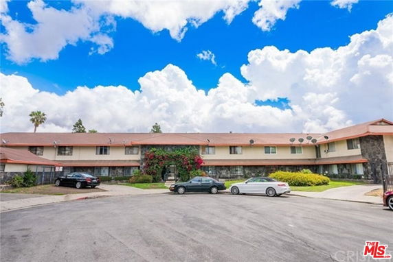 Front view of a two-story apartment building with a large parking area in front.