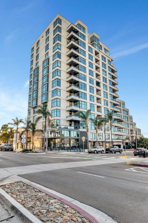 Front view of a multi-story apartment building with balconies and large windows.
