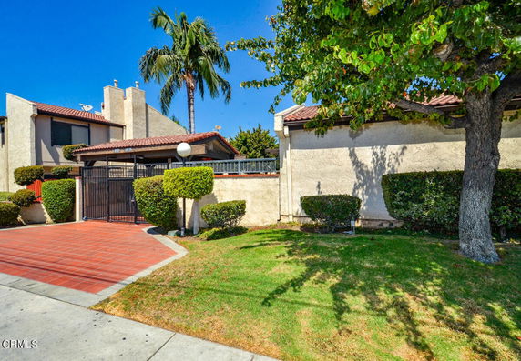 Front view of a two-story house with a gated entry and a tiled roof.