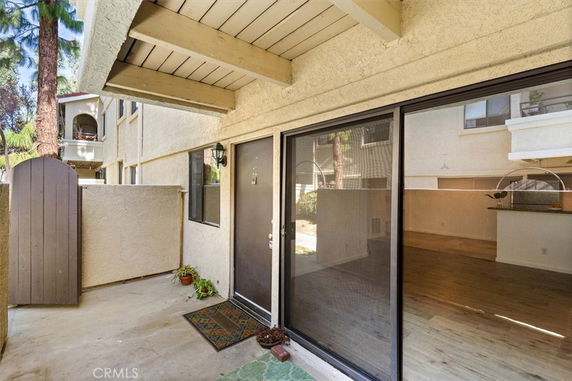 Exterior view of an apartment with sliding glass doors and wooden architectural details.