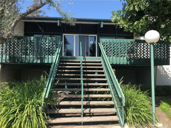 Front view of a house with a staircase and wooden railing.