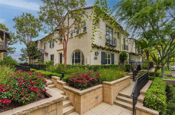 Front view of a two-story house with balconies and landscaped garden.