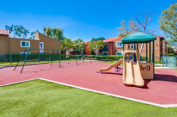 Outdoor playground with slides and swings surrounded by residential buildings.