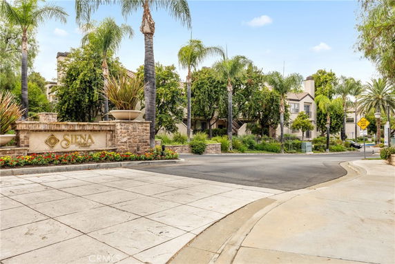 Front view of a residential complex with palm trees and a Siena Village sign.
