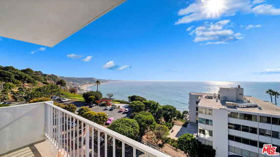 Panoramic view from a balcony overlooking the ocean and adjacent buildings.