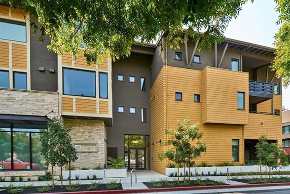 Front view of a modern multi-story building with a mix of wood and stone facade.