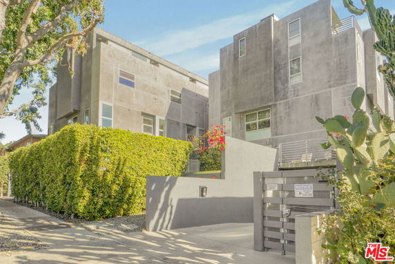 Front view of a modern multi-story building with a concrete facade and large windows.