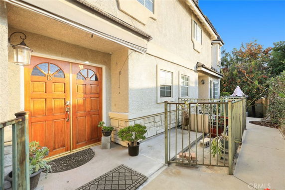 Front view of a two-story house with a double wooden door entrance and a small gated area.