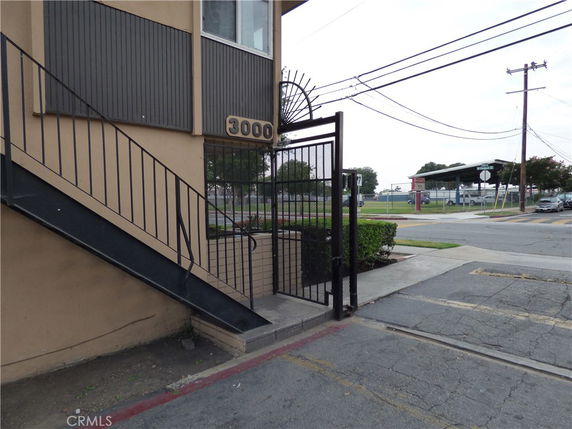 Exterior view of a building with stairs and a gated entrance.