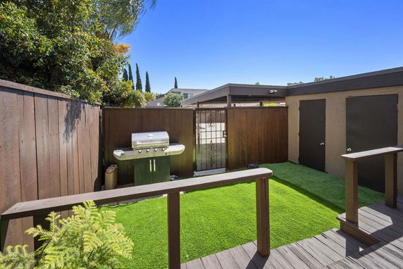 Outdoor area with artificial grass and a barbecue grill.