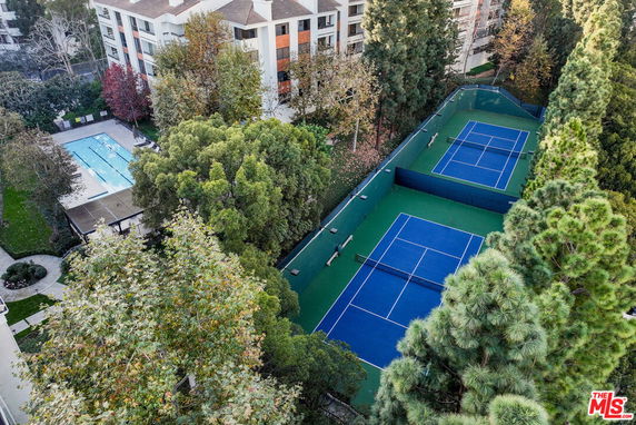 Aerial view of outdoor tennis courts adjacent to a swimming pool.