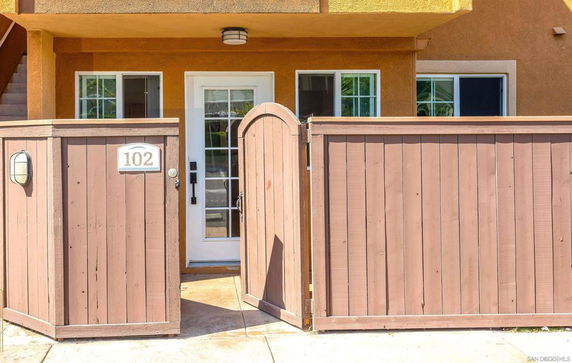 Front view of an entrance with a wooden gate and glass door.