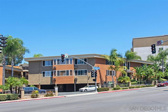 Front view of a multi-story apartment building at a street corner.