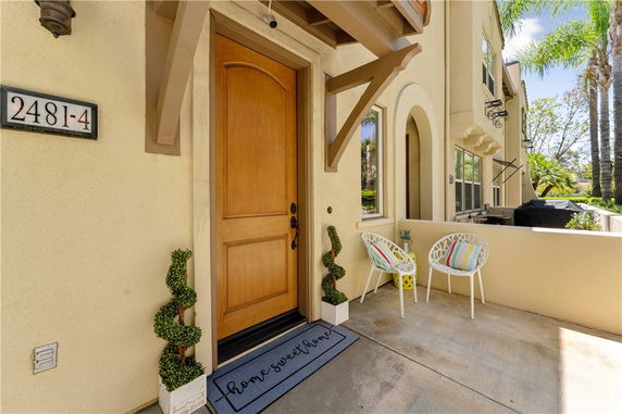 Front view of an entryway to a residential building with a door, window, and small sitting area.
