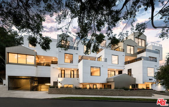 Front view of a modern multi-story building with geometric design and balconies.