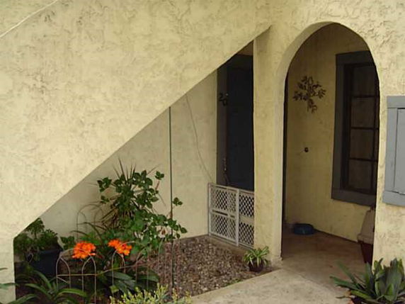 Front view of a house with an arched entryway and decorative plants.