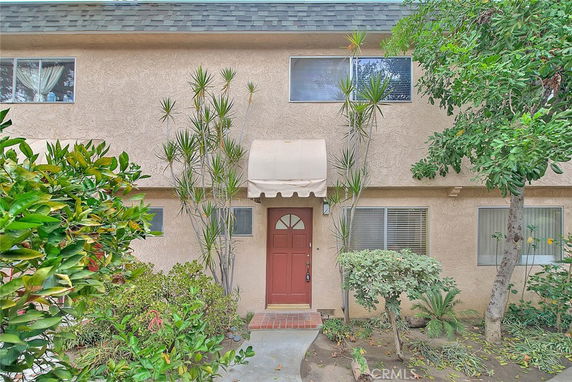 Front view of a two-story house with a red door and awning.