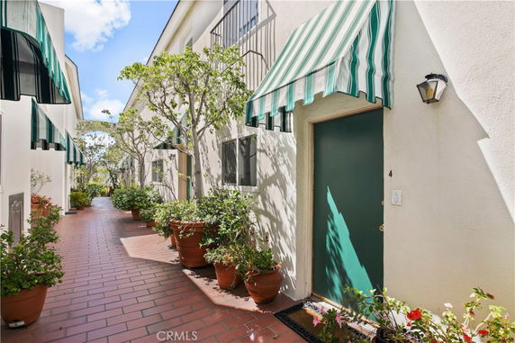 Front view of a building with green awnings and potted plants along a walkway.