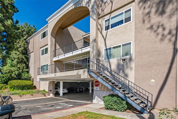 Front view of a multi-story building with an archway and exterior staircase.