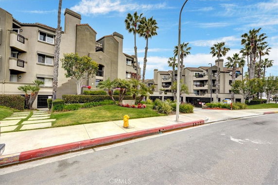 Front view of a multi-story residential building with balconies and palm trees.