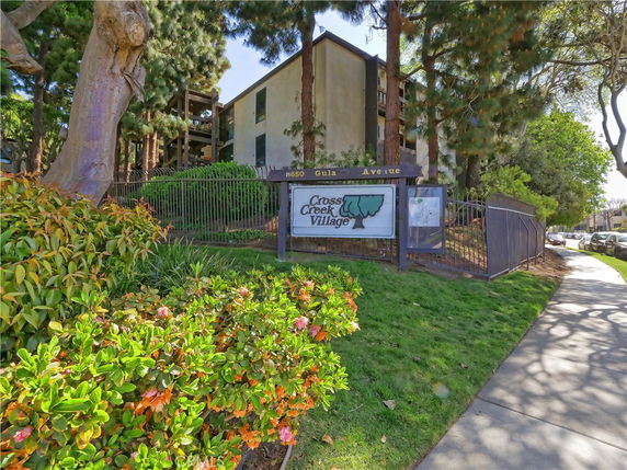 Front view of a multi-story residential building complex with a sign reading 'Cross Creek Village'.