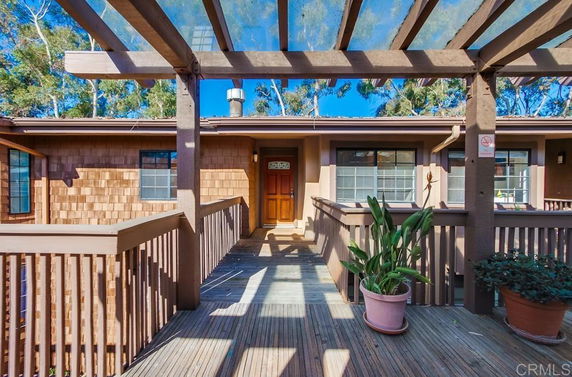 Front view of a house with a wooden walkway and pergola.