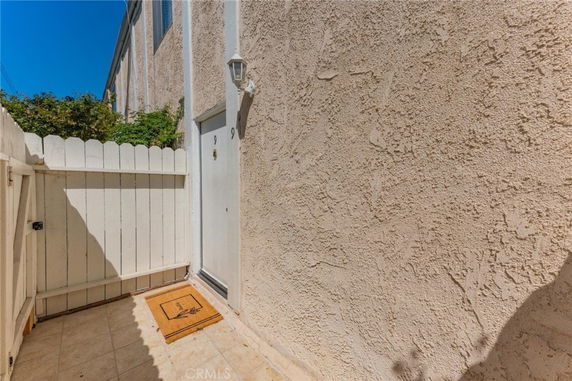 Front view of a residential unit entrance with a white door and small fenced patio.