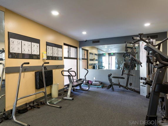 Indoor gym area with exercise equipment and mirrors on the walls.