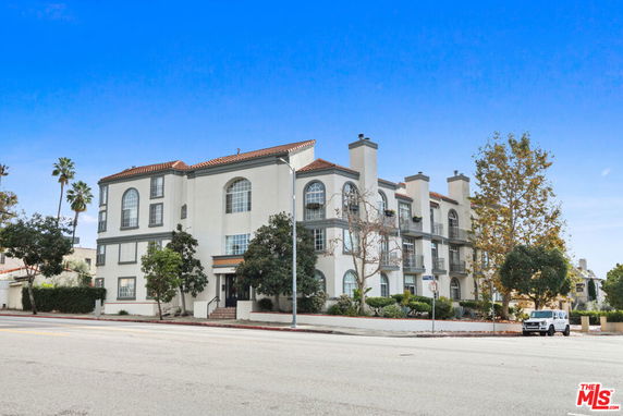 Front view of a multi-story residential building with arched windows and balconies.