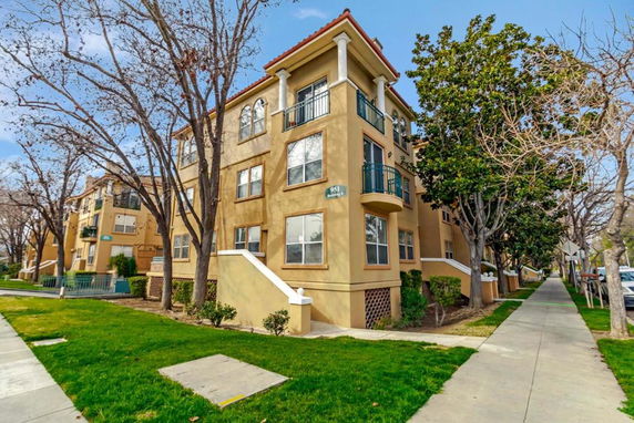 Front view of a multi-story apartment building with beige exterior and balconies.