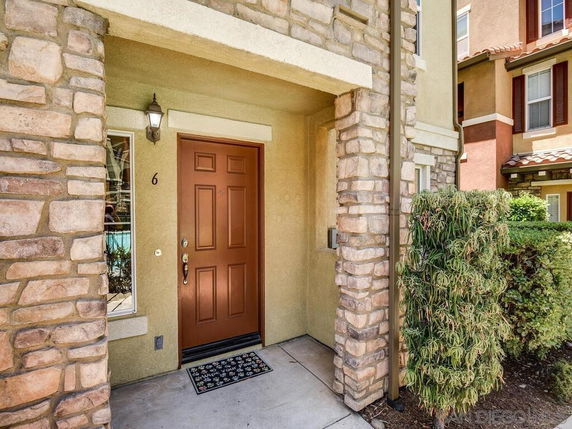 Front view of a house entrance with a brown door and stone facade.