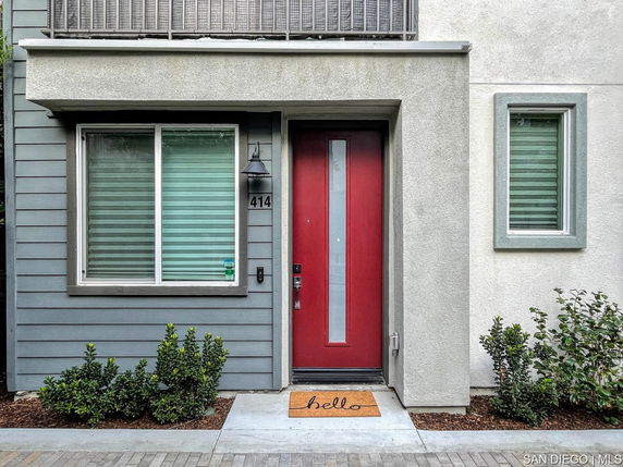 Front view of a contemporary house entrance with a red door and windows.