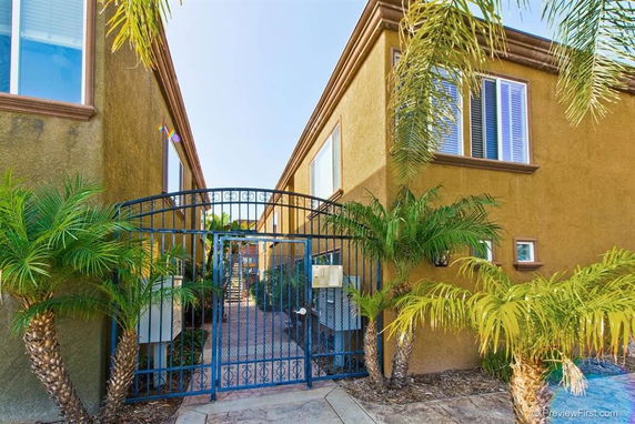 Front view of a two-story building with gated entrance and palm trees.
