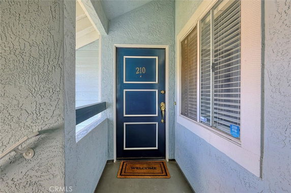 Entrance view of a residential building with a blue door and welcome mat.
